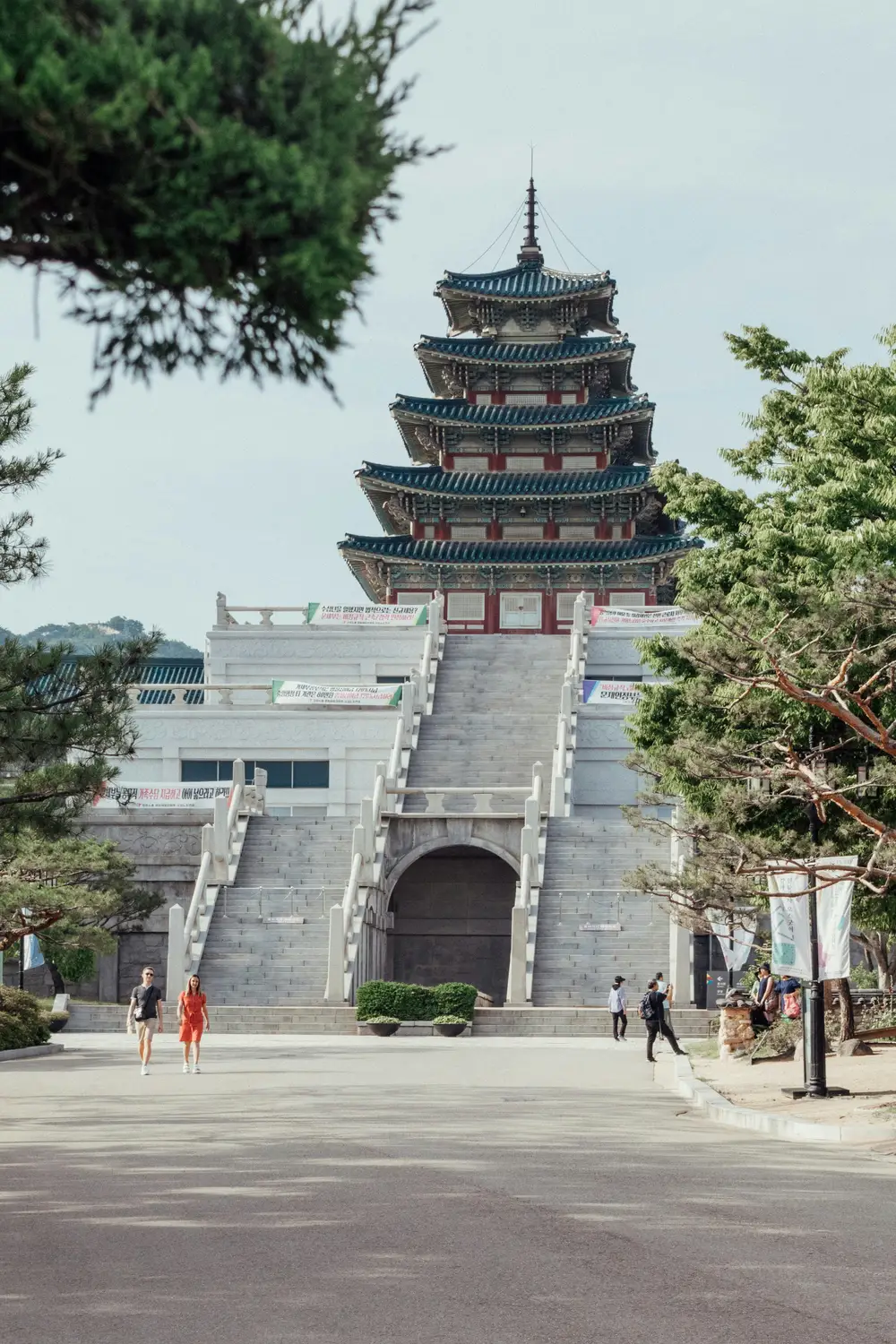 Multi-tiered traditional Korean palace building framed by trees on a sunny day at Gyeongbokgung Palace in Seoul.