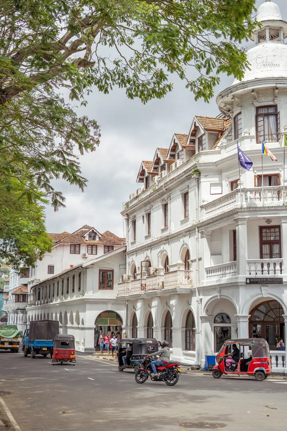 Colonial-era white building and busy street with tuk-tuks and traffic in Kandy, Sri Lanka.