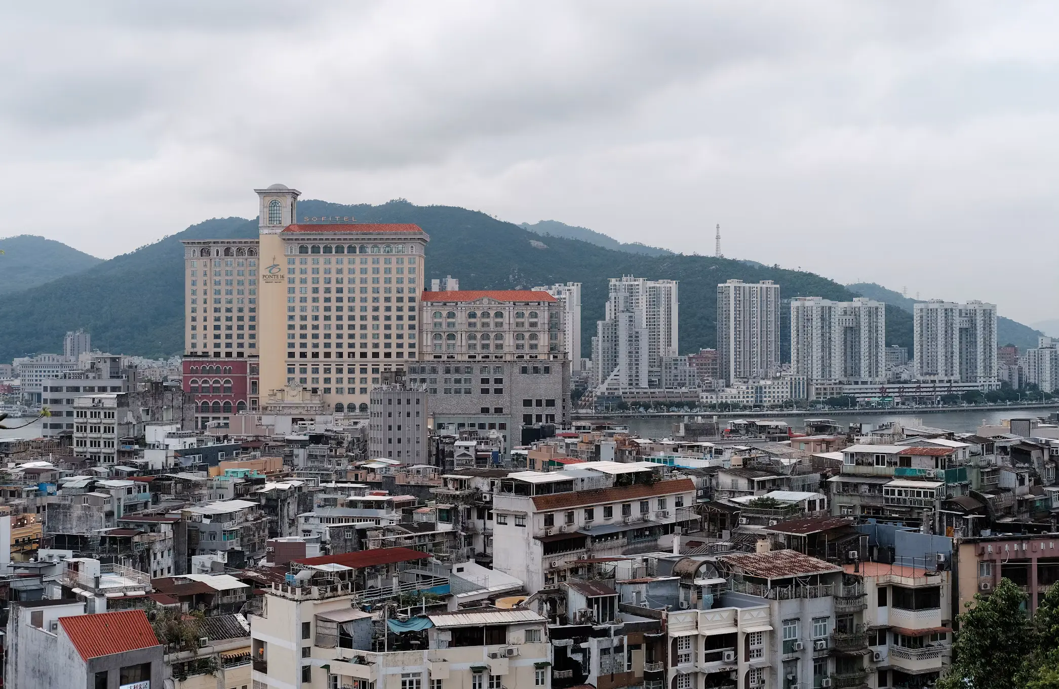 Aerial view of Macau's old town rooftops with hillside high-rises in the background