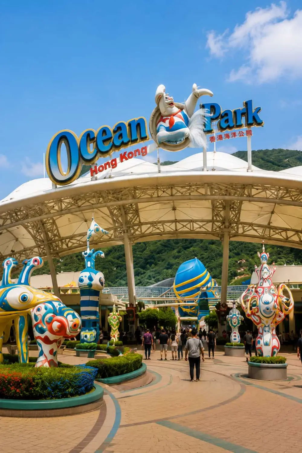 Colorful entrance to Ocean Park theme park with sculptures and visitors in Hong Kong.