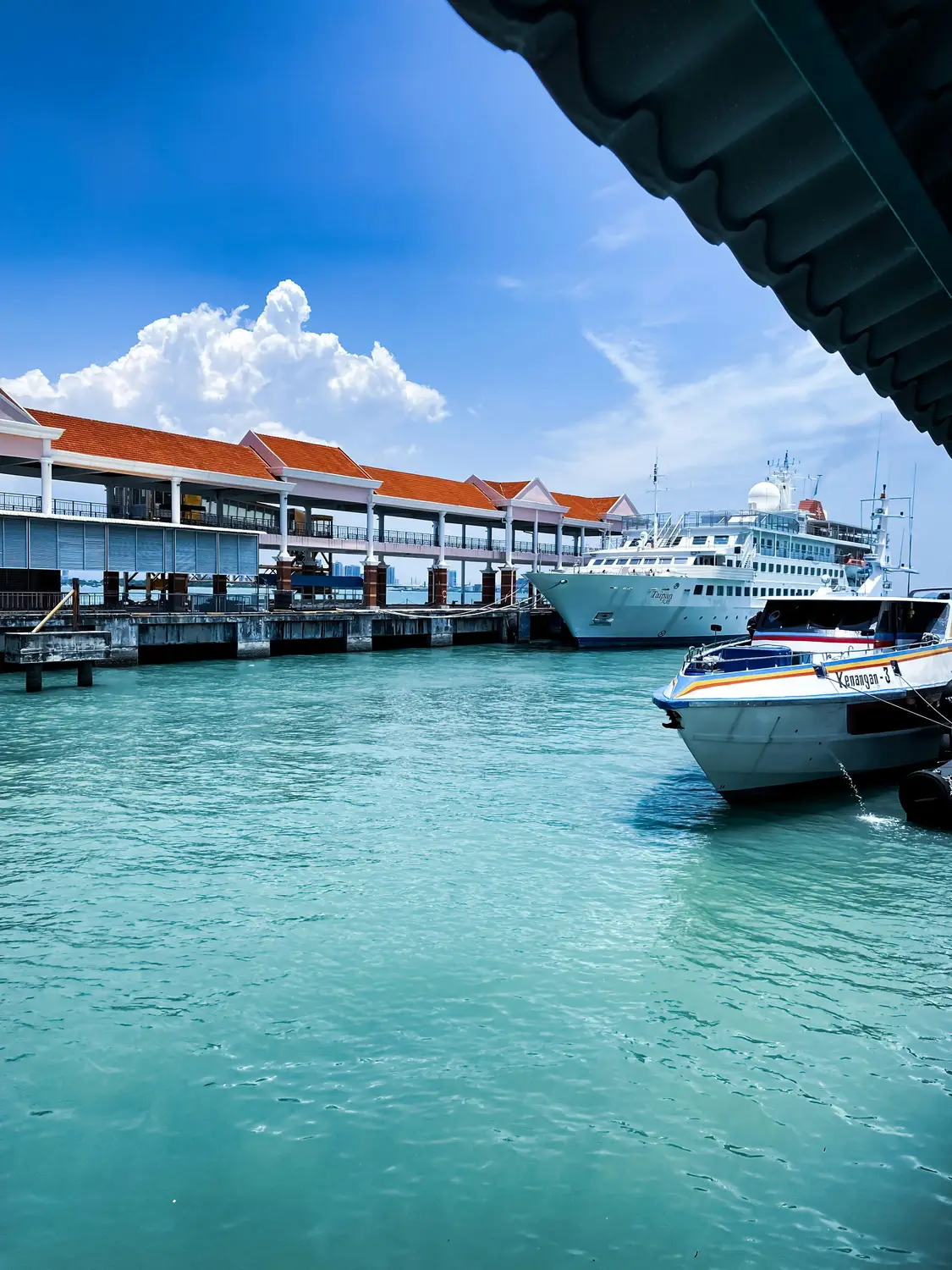 Aerial view of Penang ferry terminal jetty with turquoise sea water and boats docked in Georgetown Penang Malaysia