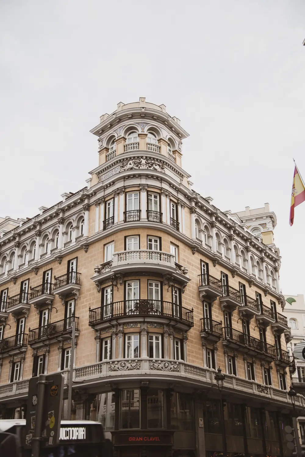 Ornate corner facade of a grand period building with balconies and a domed turret, viewed from street level.