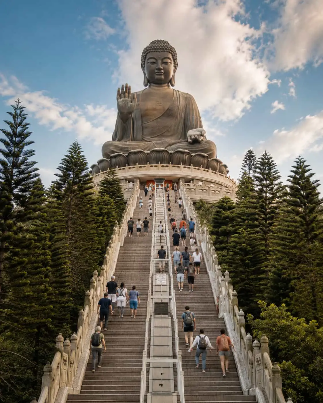 Tian Tan Big Buddha statue atop a long staircase surrounded by forested hills on Lantau Island in Hong Kong.