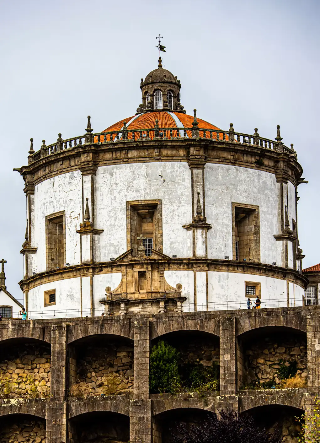 A large white circular church with an orange-tiled dome and stone arches in front.