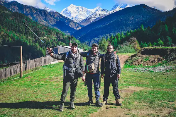 Group of trekkers posing together on a grassy trail with snow-capped mountains in the background, Nepal
