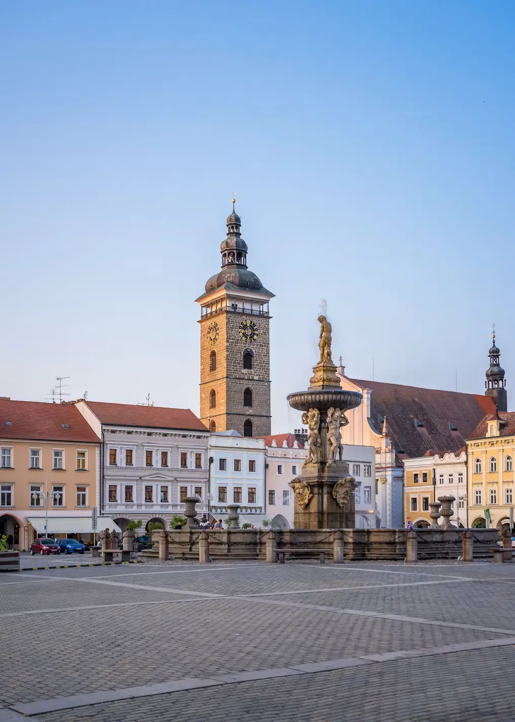 Black Tower and ornate Samson Fountain in a quiet town square at golden hour