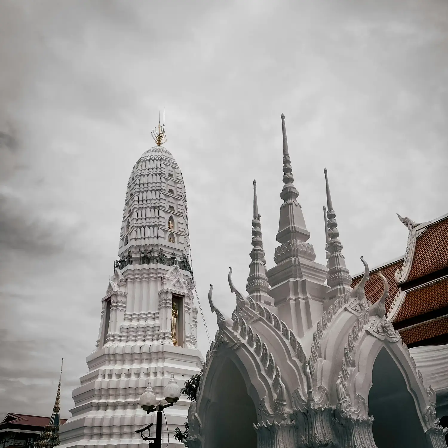 Black and white long exposure photograph of ancient white chedis and temple spires with ethereal motion blur effect, Thailand