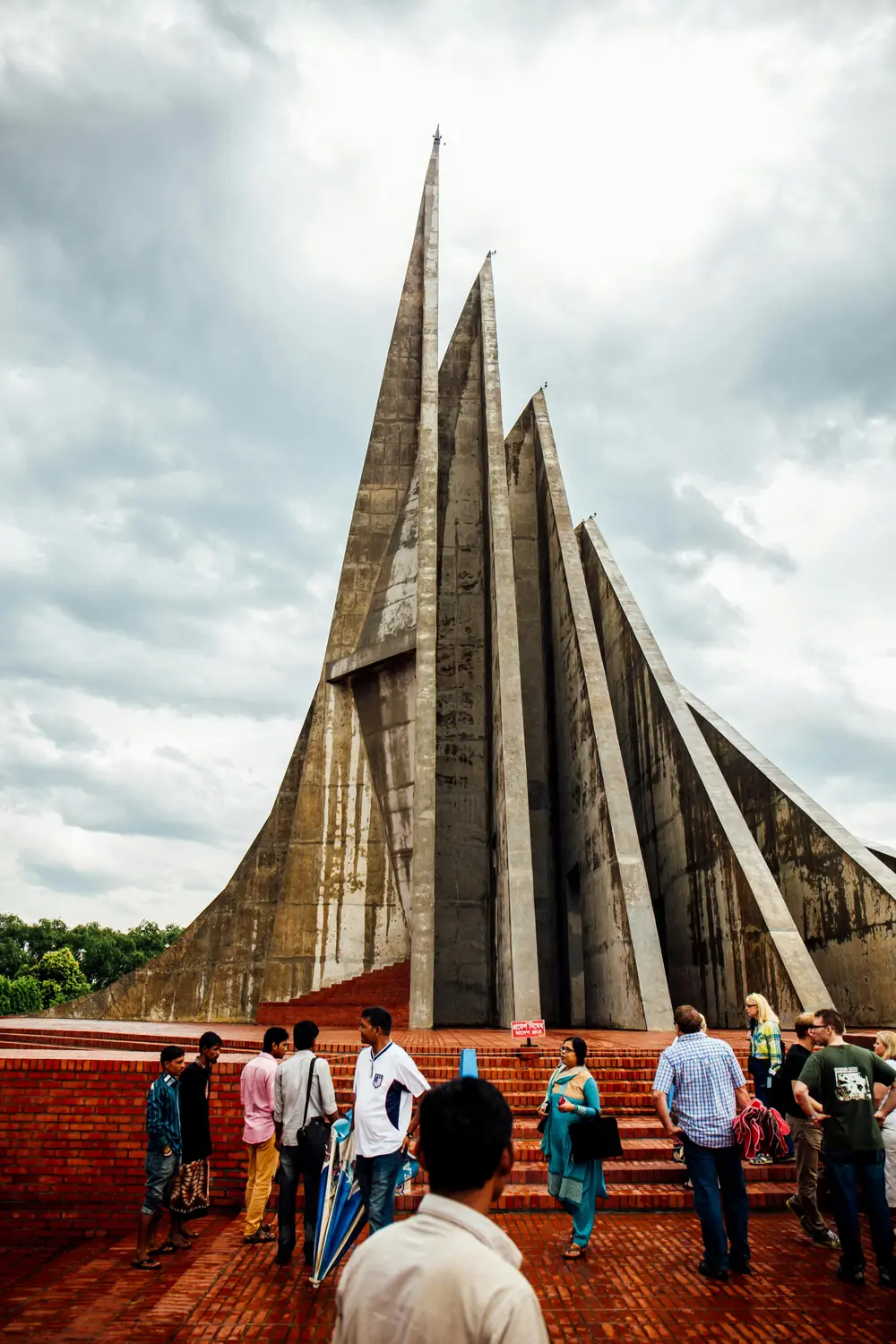 Visitors gathered at the towering concrete spires of Jatiyo Smriti Soudho National Martyrs Memorial on brick steps, Savar, Dhaka, Bangladesh