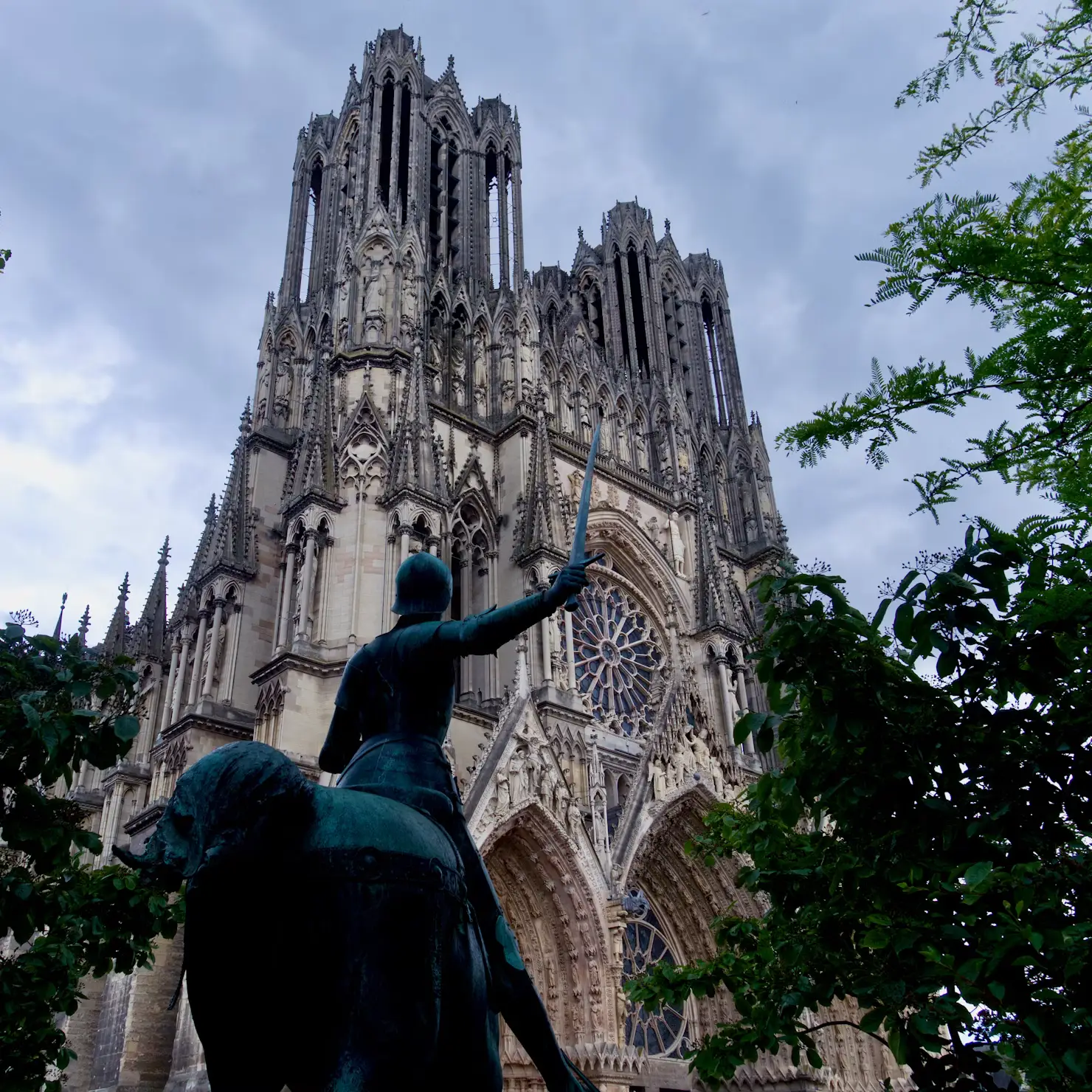 Statue of Joan of Arc on horseback in front of Reims Cathedral's Gothic facade
