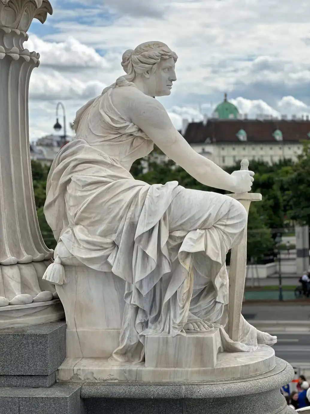 White marble seated statue overlooking the square and distant city skyline.