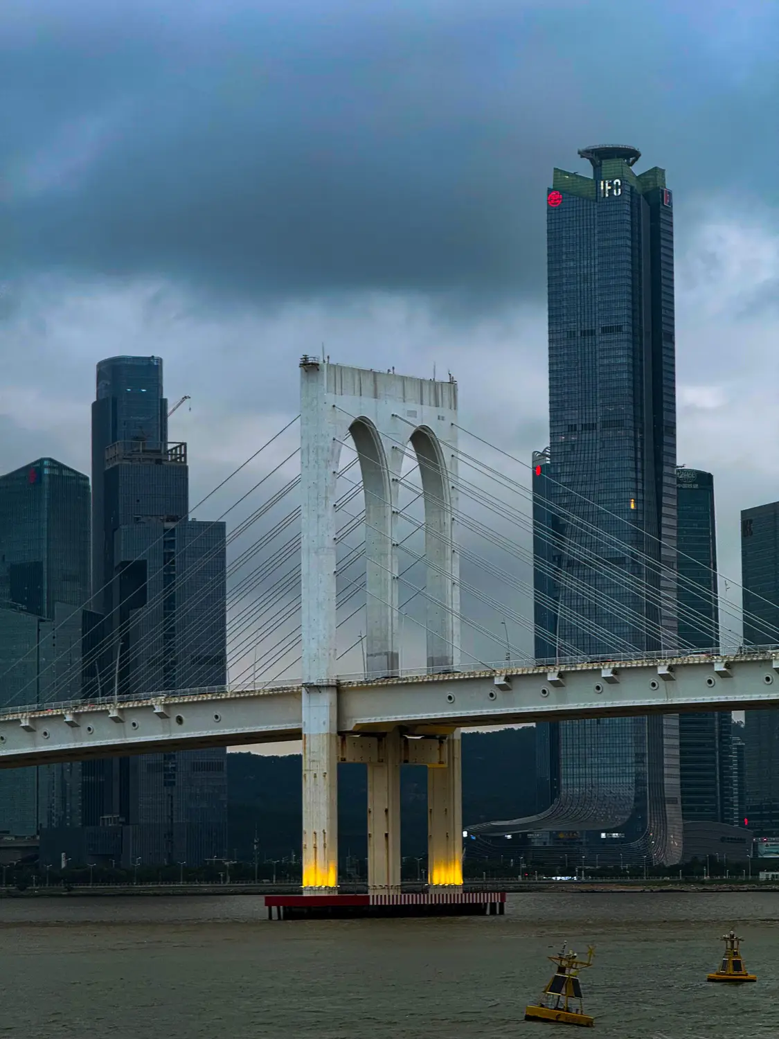 Sai Van Bridge spanning the water with Macau's skyline of skyscrapers behind it