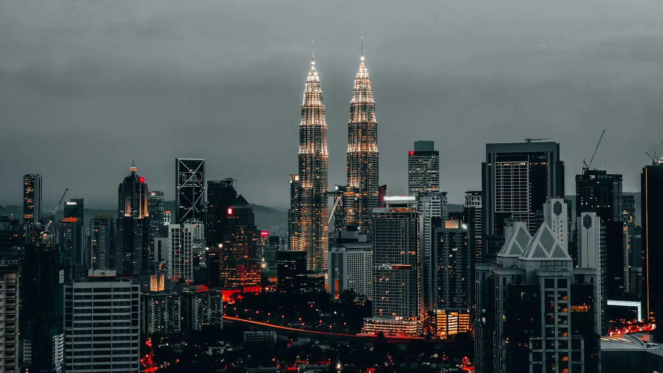 Petronas Twin Towers illuminated at night in Kuala Lumpur Malaysia skyline with city lights and surrounding skyscrapers