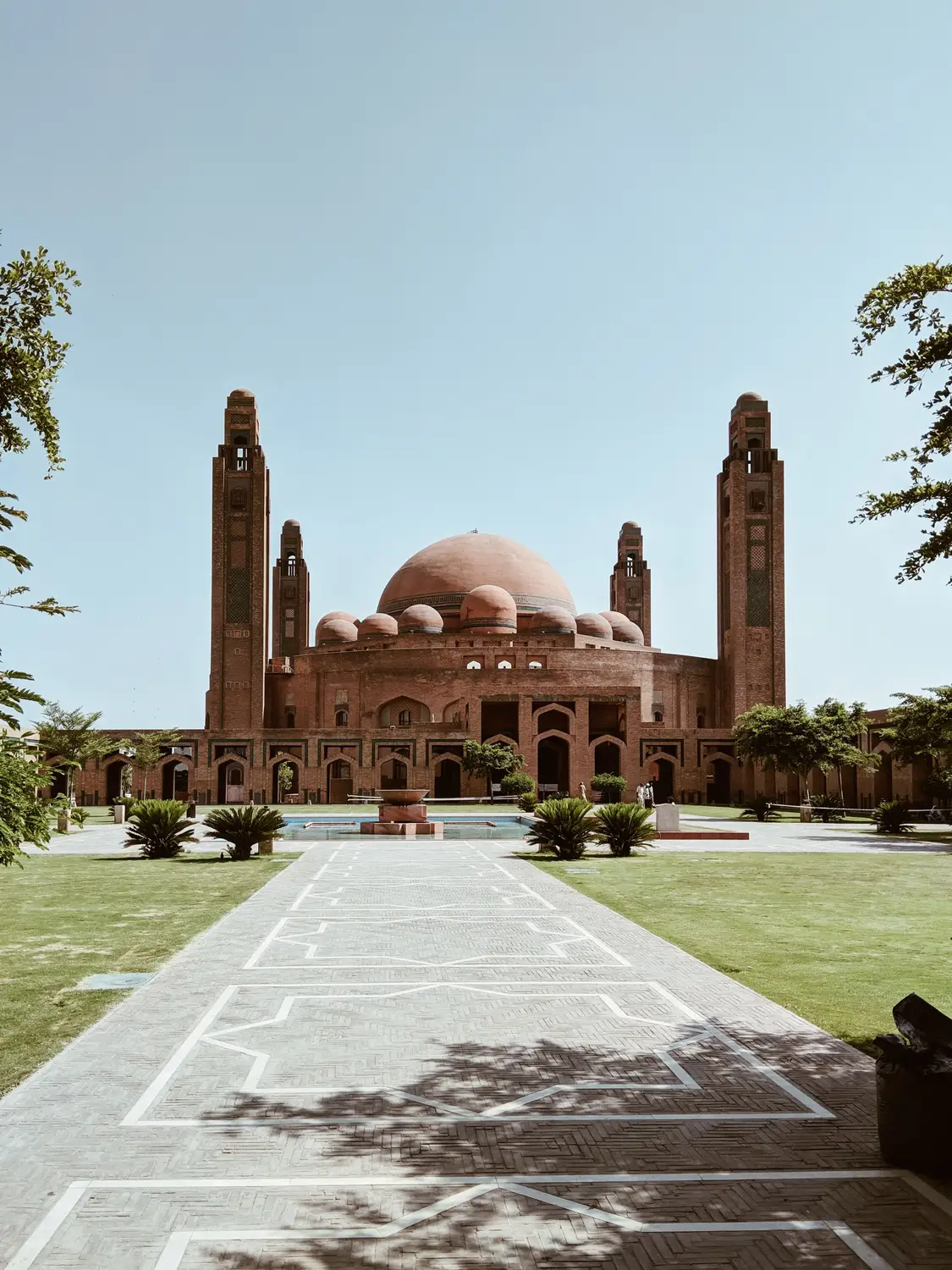 Grand Jamia Mosque red brick dome and minarets with paved courtyard and green lawn Lahore Pakistan