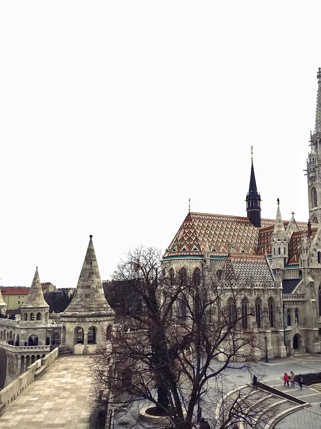 Church with patterned roof beside the white towers of Fisherman’s Bastion.