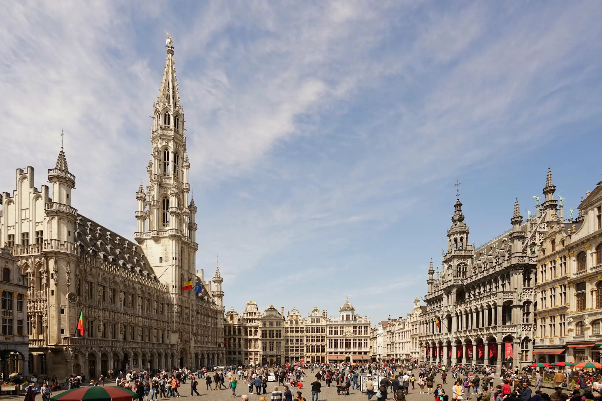 Grand Place square in Brussels, Belgium, with the ornate Town Hall spire and guildhalls under a wide sky
