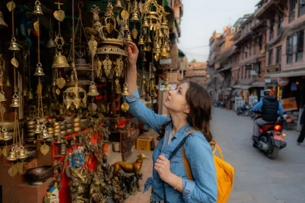 Woman browsing brass bells and handicrafts at a street market stall, Kathmandu, Nepal