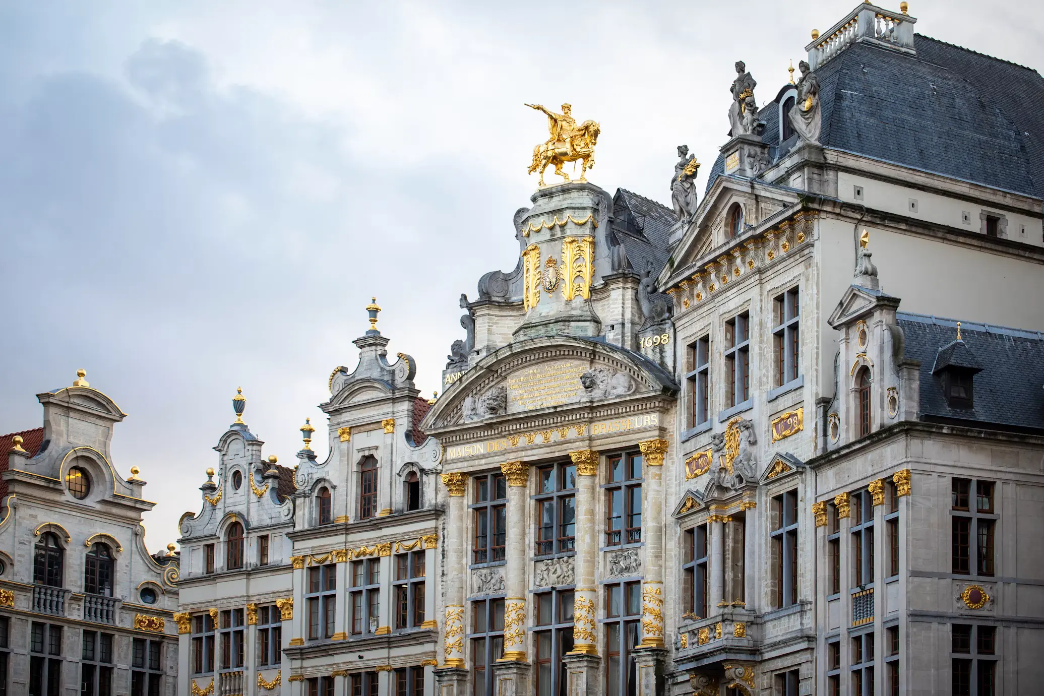 Golden statue atop an ornately gilded guild house facade in Brussels' Grand Place, inscribed "Maison des Brasseurs.