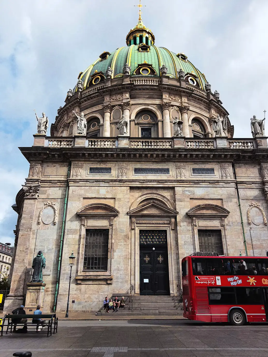 Frederik's Church (Marble Church) in Copenhagen with its green dome and a red tour bus outside
