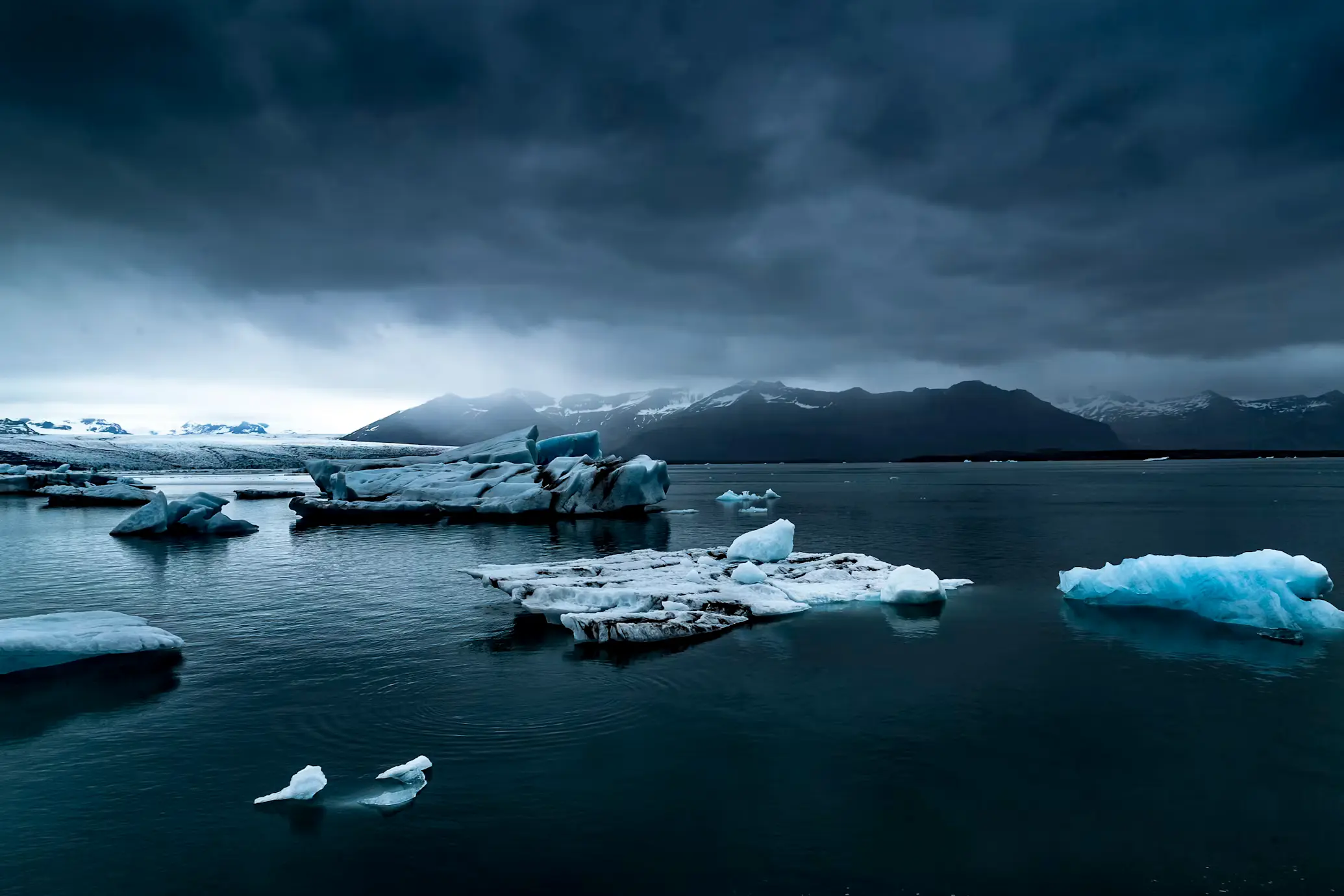 Icebergs floating in a dark glacial lagoon under a stormy sky, Iceland.