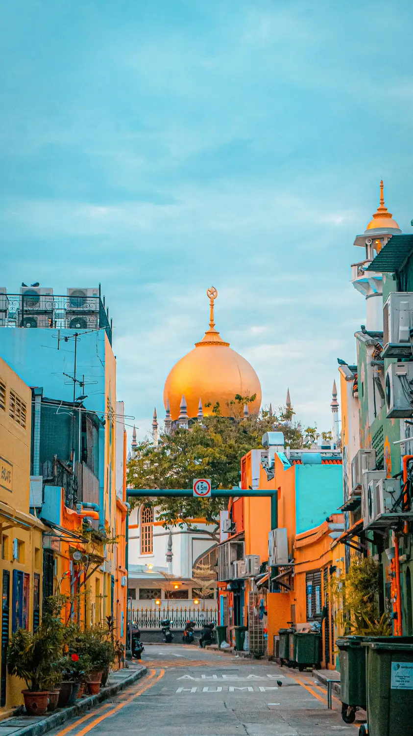 Colorful shophouses lining narrow Arab Street with Sultan Mosque golden dome visible in background Kampong Glam Singapore