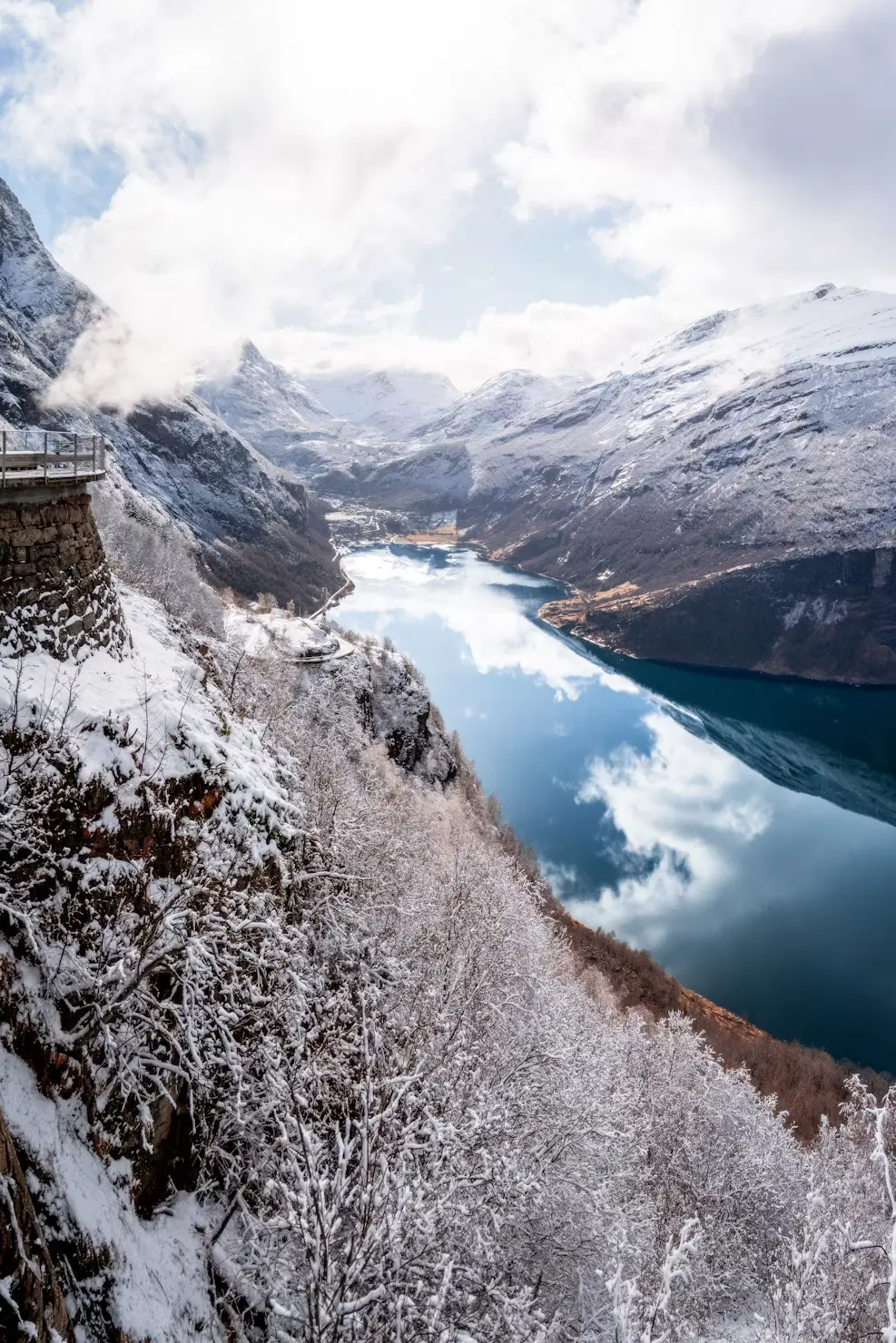 White waterfront buildings at the foot of a towering, snow-covered mountain peak.