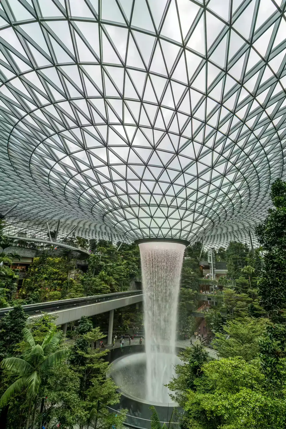 Rain Vortex indoor waterfall at Jewel Changi Airport Singapore beneath a geometric glass dome canopy surrounded by lush tropical gardens