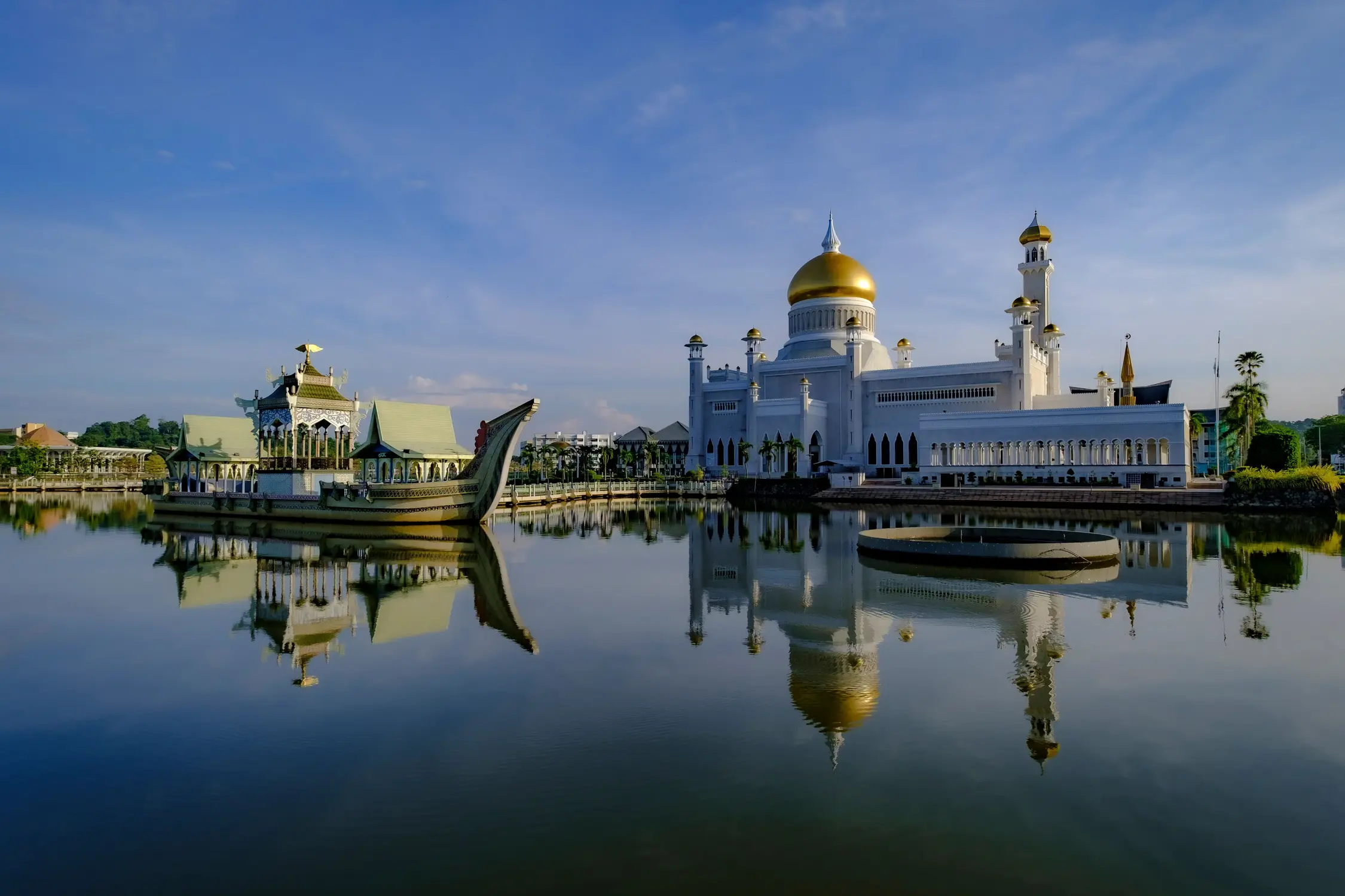 Sultan Omar Ali Saifuddien Mosque in Bandar Seri Begawan Brunei with golden dome and white marble exterior reflected in calm lagoon water alongside traditional royal barge