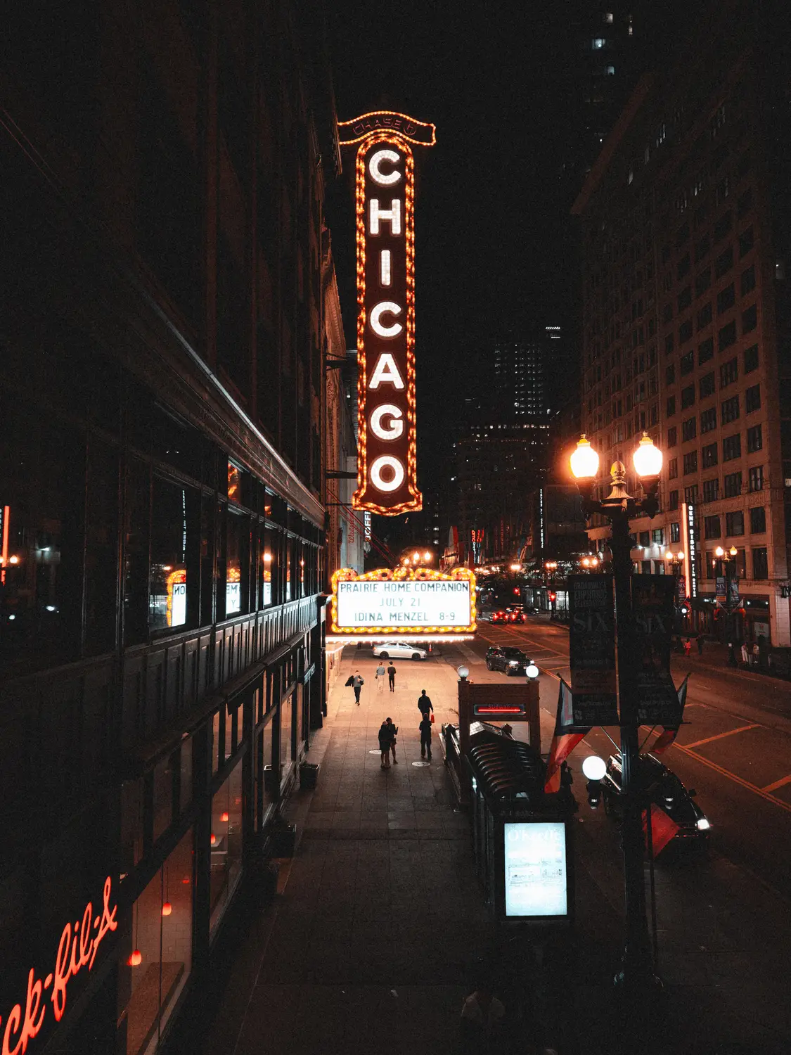 The glowing Chicago Theatre marquee lighting up a downtown street at night.