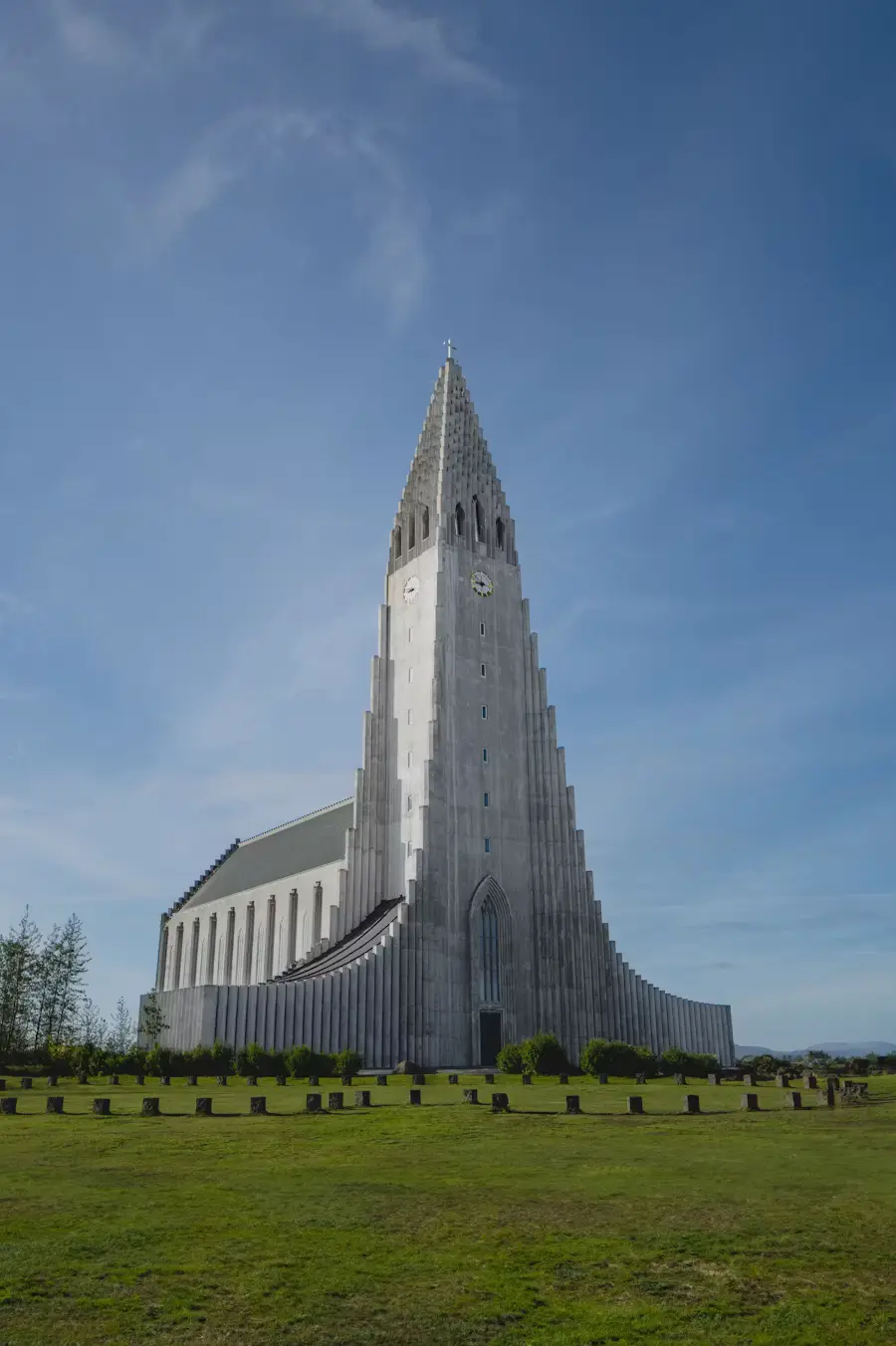 Tall, ribbed concrete church tower rising above a green lawn, Reykjavík, Iceland.