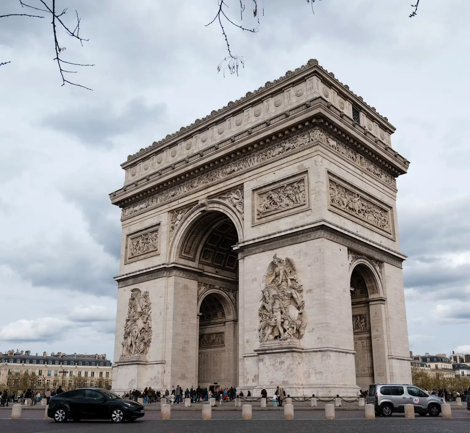 Arc de Triomphe monument in Paris with traffic circling below on a cloudy day