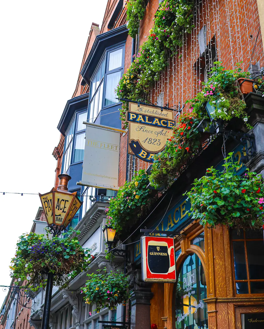 Ornate pub facade decorated with hanging flower baskets and vintage signage, Ireland.