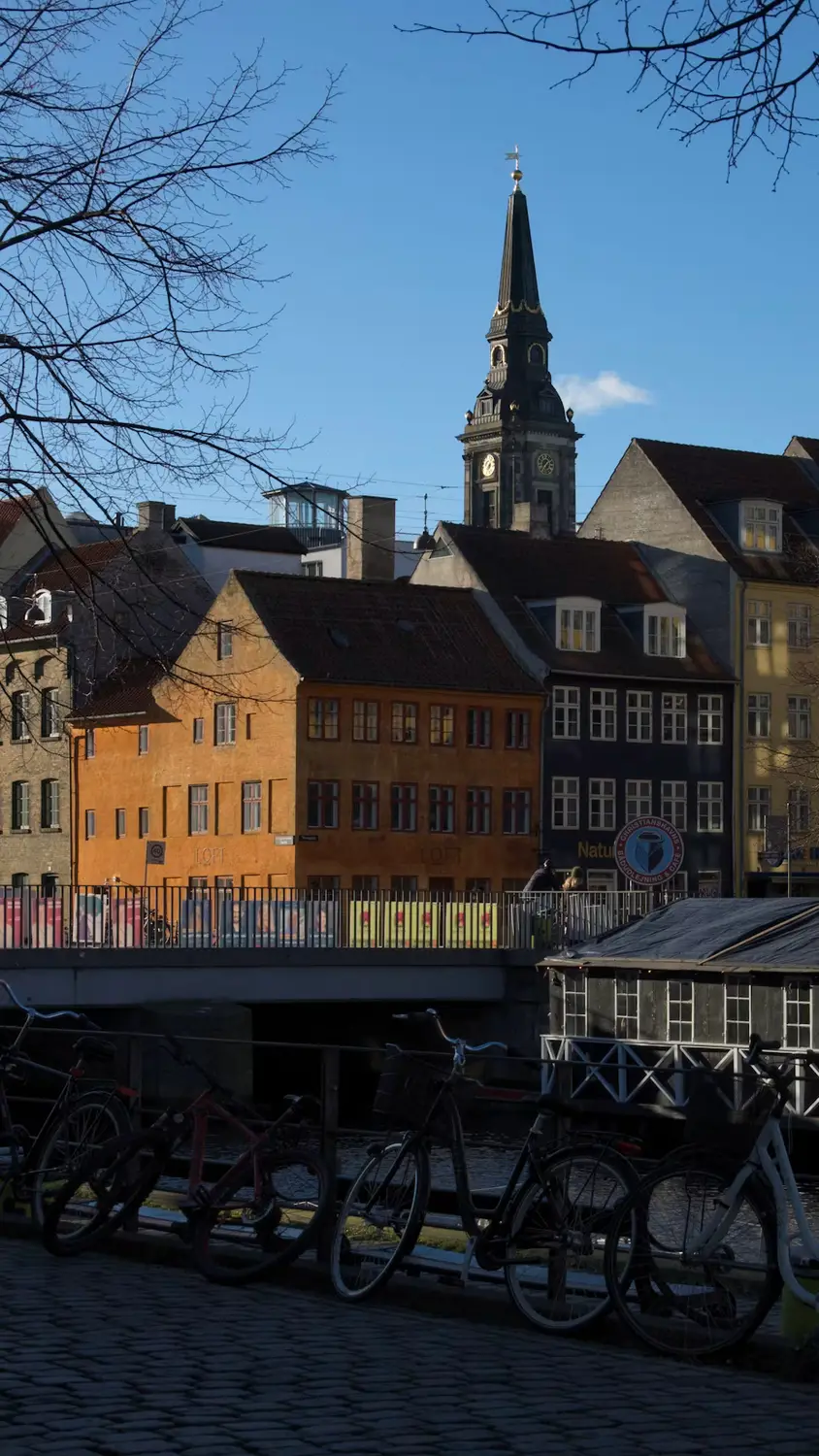Colorful Nyhavn townhouses and a church spire at dusk with bicycles parked along the canal