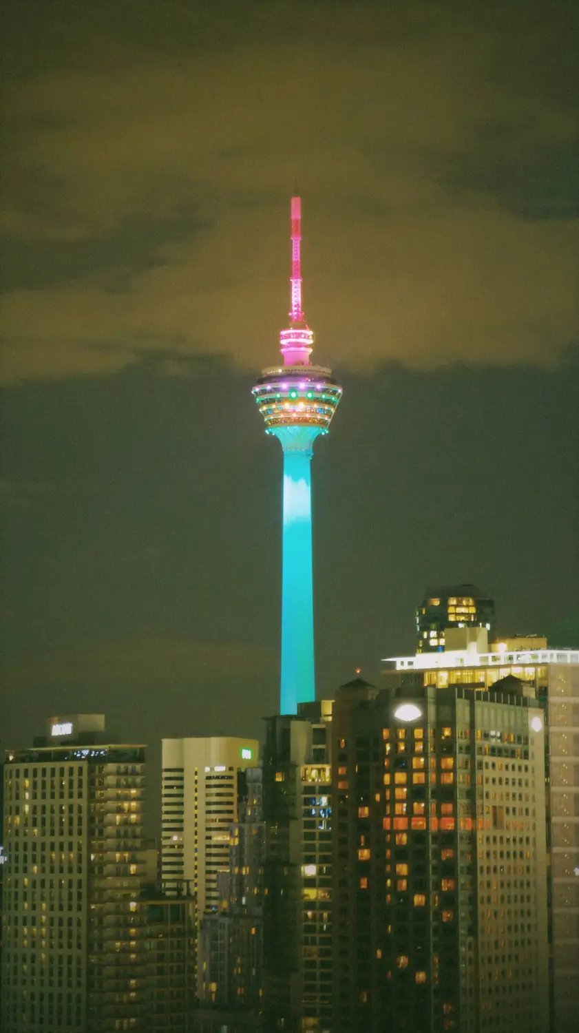 Kuala Lumpur Tower KL Tower illuminated with colorful lights at night against city skyline and dark sky Malaysia