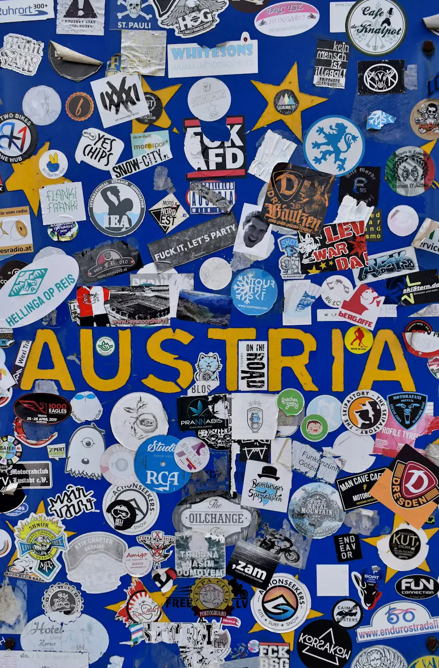 A blue wall covered densely with colorful travel stickers and pins, prominently featuring the word "AUSTRIA" in yellow lettering.