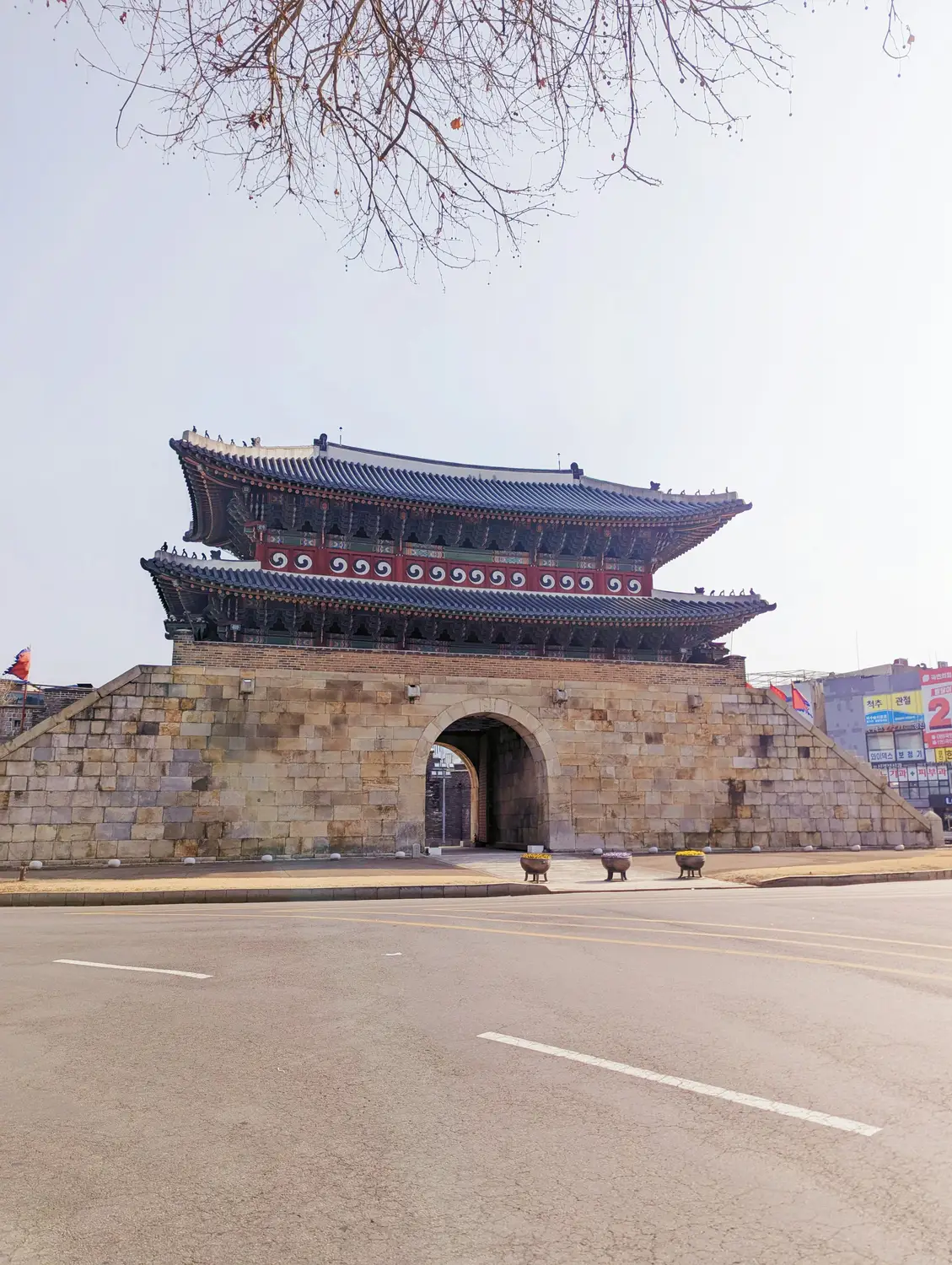 Namdaemun Gate, a traditional Korean fortress gate with a tiled roof, beside an empty road in Seoul.