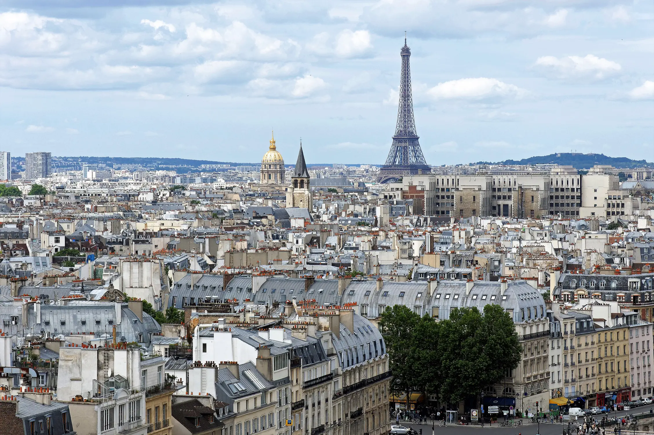 Paris cityscape view from above showing the Eiffel Tower and rooftops with Les Invalides dome in the background