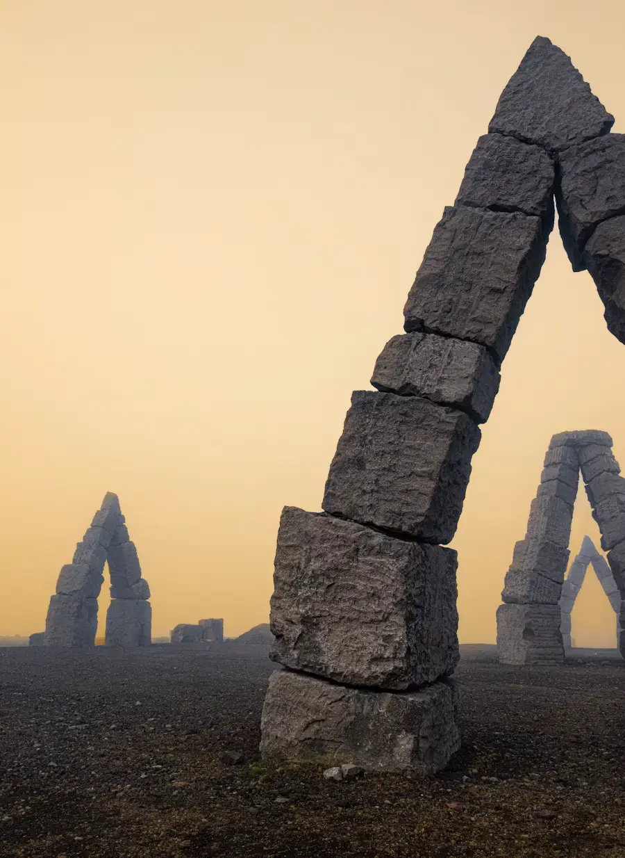 Basalt rock arch formations on black sand under a hazy golden sky, Iceland.