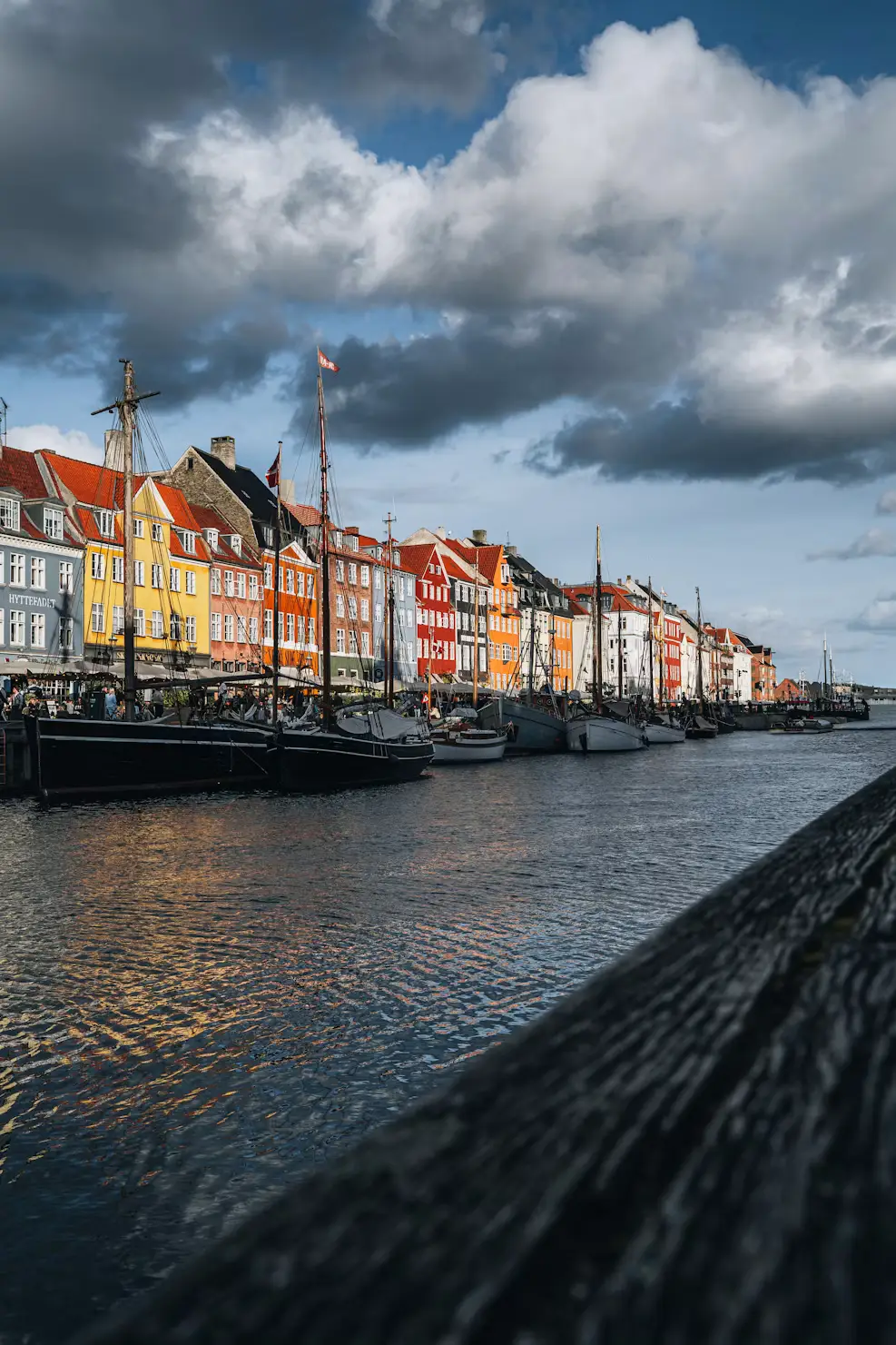 Nyhavn canal in Copenhagen with colorful buildings and sailboats under a partly cloudy sky