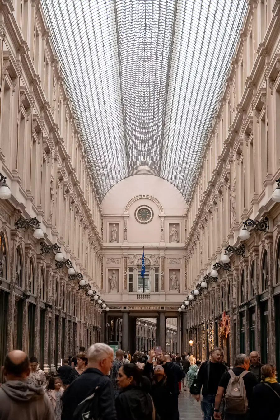 The elegant glass-roofed Galeries Royales Saint-Hubert shopping arcade in Brussels, filled with strolling visitors.
