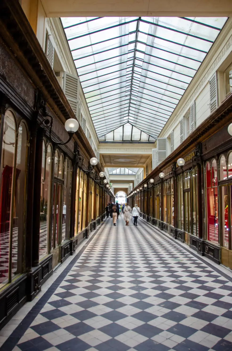 Covered shopping arcade in Paris with checkerboard floor tiles and glass-paneled roof