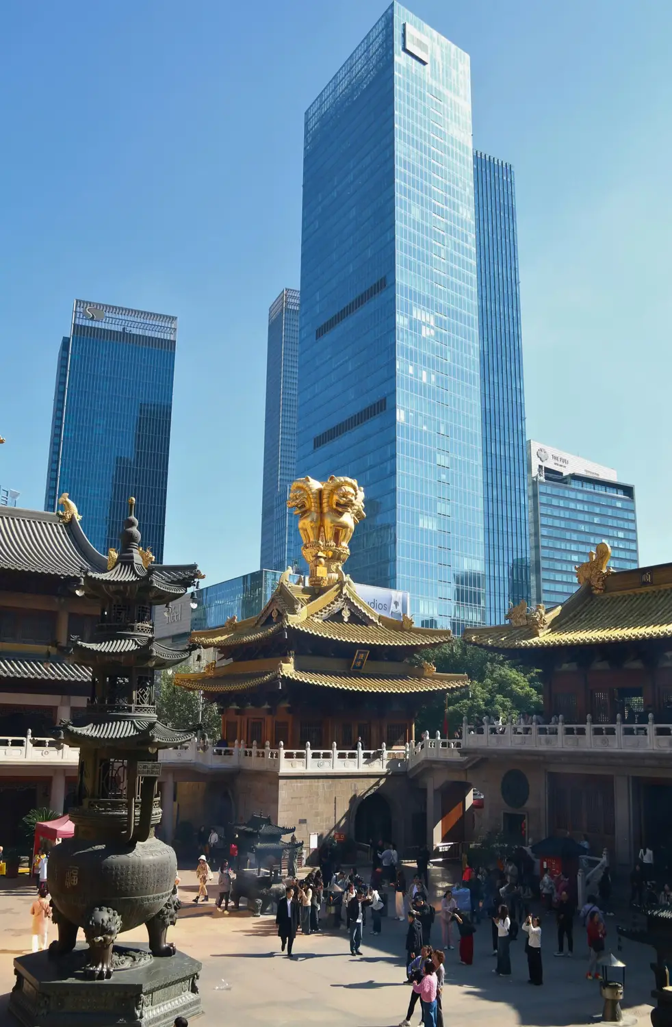 Jing'an Temple Shanghai with golden lion sculptures and traditional rooftop against modern glass skyscrapers