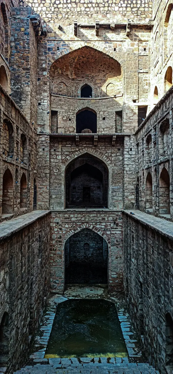 Ancient stepwell baoli with symmetrical stone arched corridors descending to water, Agrasen Ki Baoli, New Delhi, India