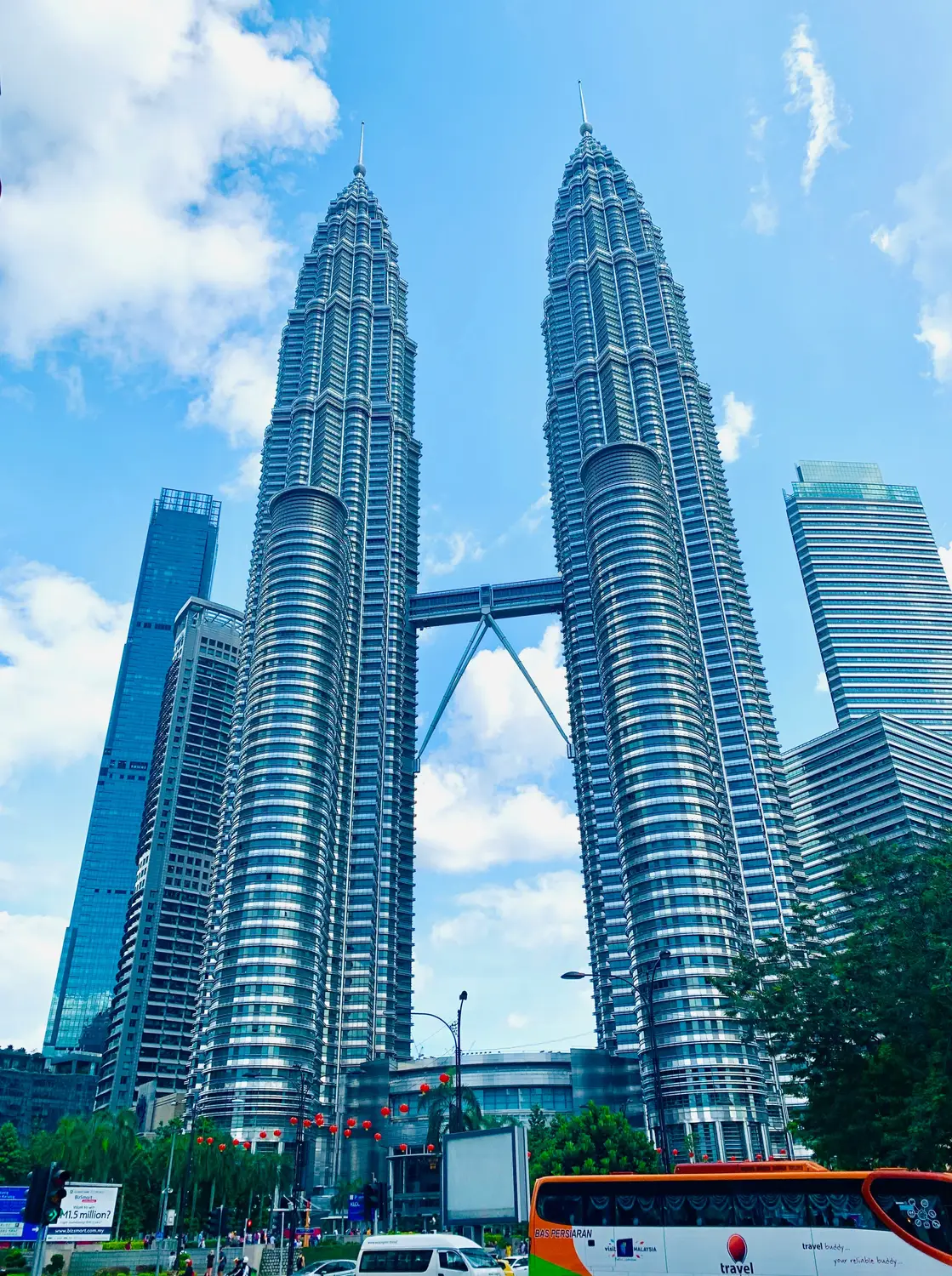 Petronas Twin Towers daytime view from ground level with sky bridge connector and surrounding skyscrapers in Kuala Lumpur Malaysia