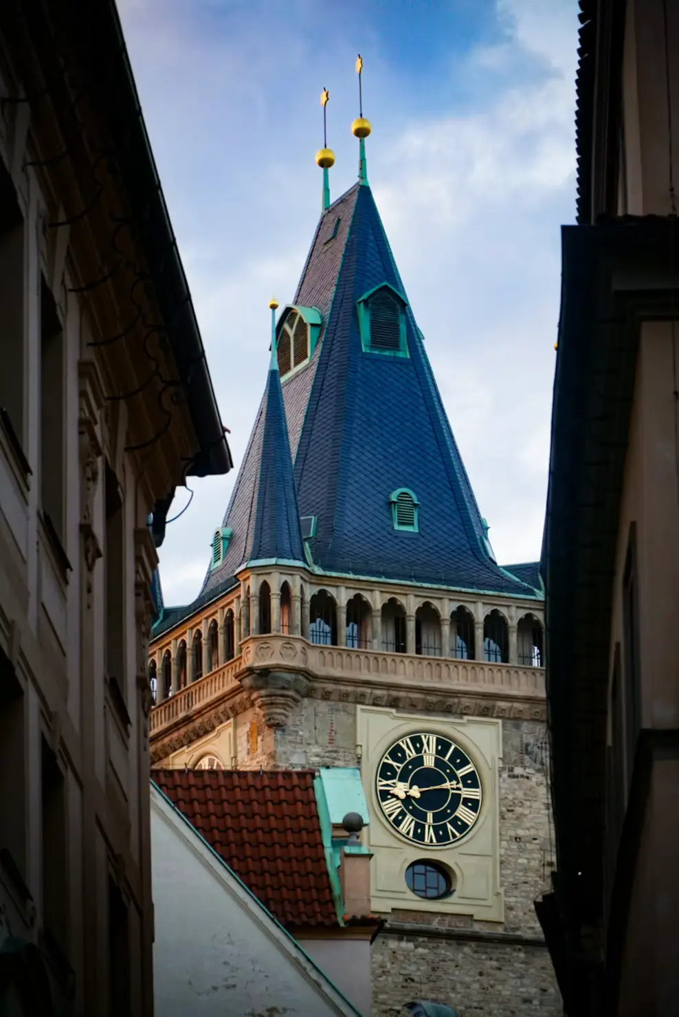 Close-up view of a spired clock tower with a blue steeple roof, seen between historic buildings