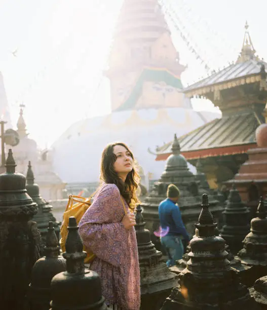 Woman with backpack walking among stupas at Swayambhunath temple, Kathmandu, Nepal