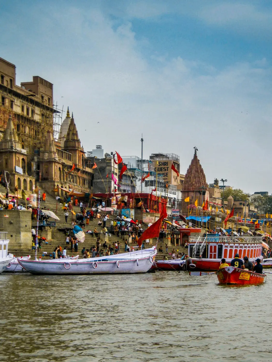 Colorful boats and pilgrims on the ghats of the Ganges River with ancient temples, Varanasi, Uttar Pradesh