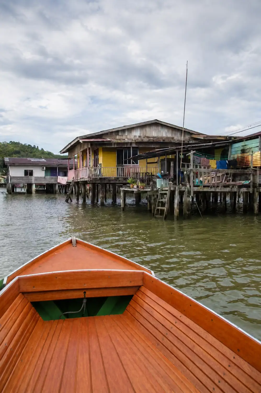Kampong Ayer water village colorful stilted wooden houses viewed from traditional wooden water taxi bow, Brunei
