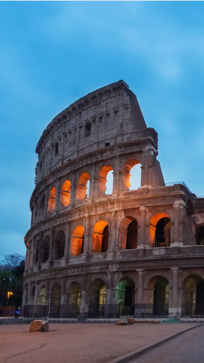 Colosseum illuminated at dusk with a dramatic cloudy sky