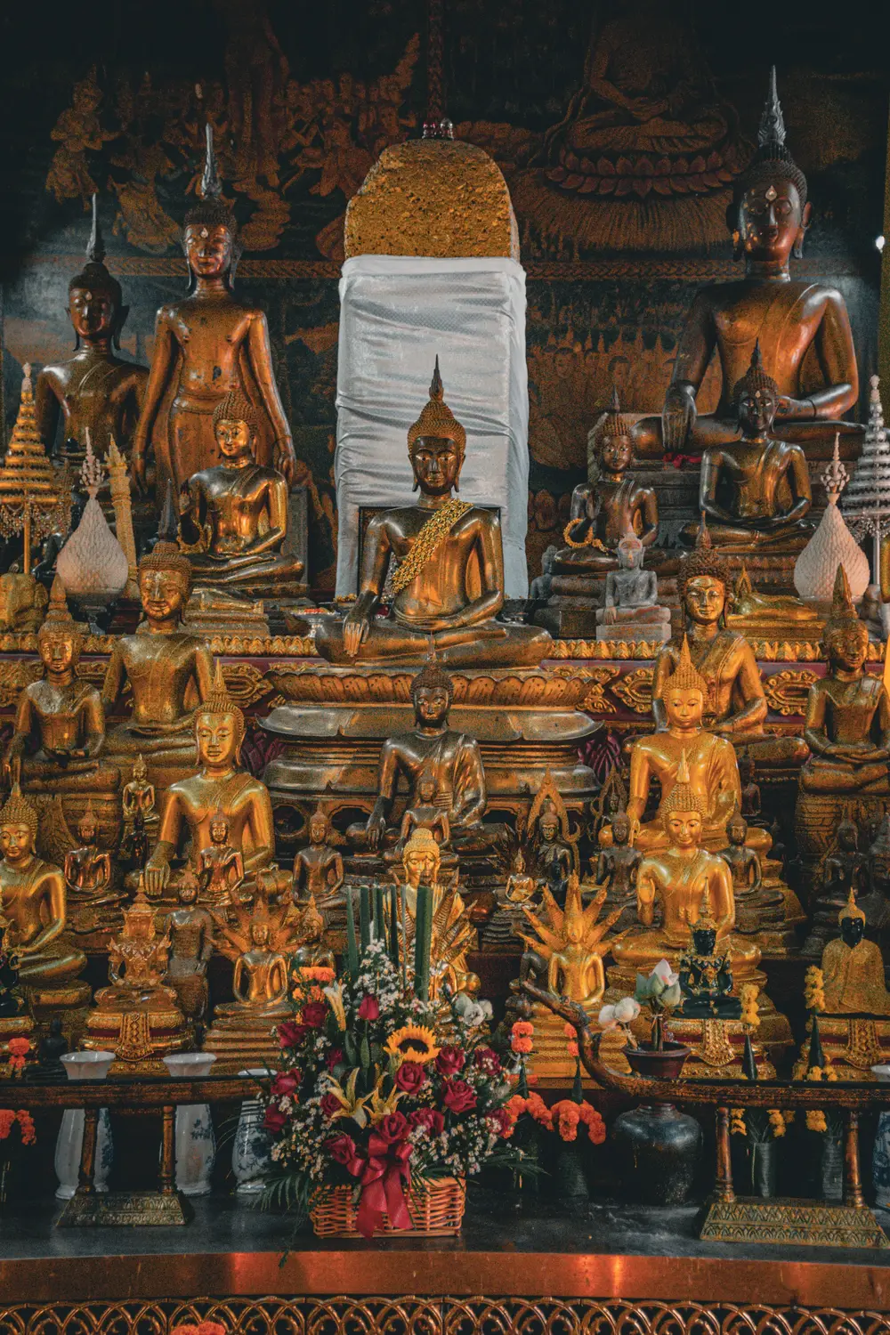 Golden Buddha statues and ornate altar inside a Buddhist temple in Laos.
