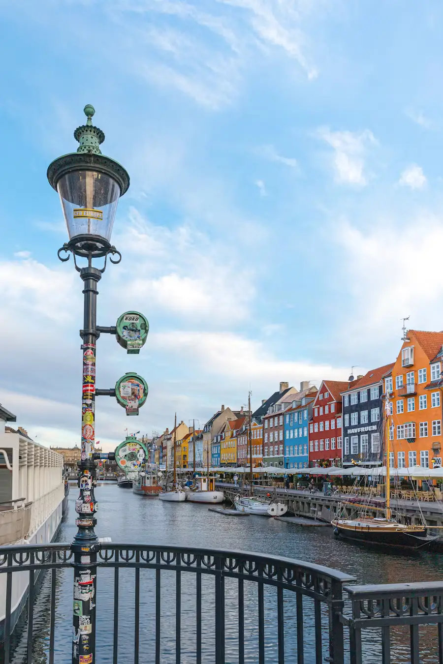 Ornate street lamp overlooking Nyhavn canal in Copenhagen with colorful waterfront buildings and boats